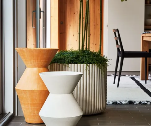 Decorative planters and a chair next to a large window in a modern interior setting.