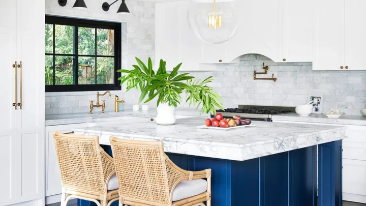 Hamptons kitchen with large blue central island and marble splashback.