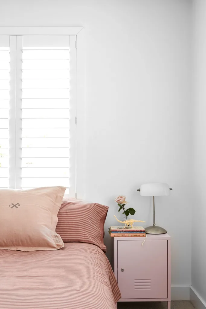 White bedroom with pink bedlinen and bedside table