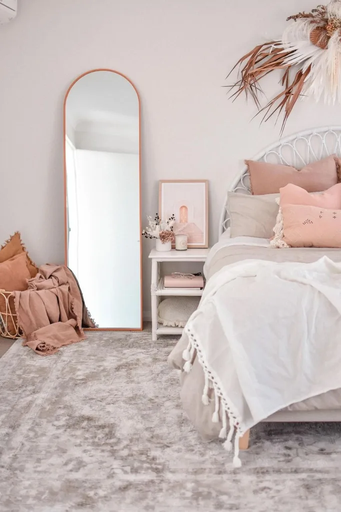 Bedroom with pink tonal palette and curved mirror and bedhead
