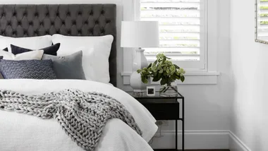 Black and white Hamptons style bedroom with warm waffle quilt on the bed.