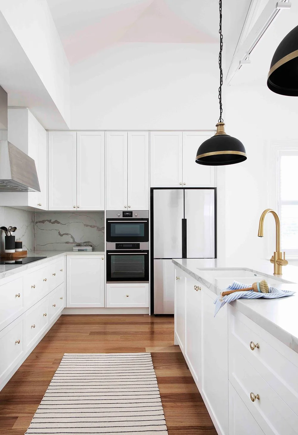 White and marble kitchen with shaker cabinets and gold hardware