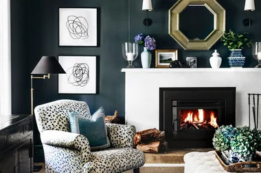 Cozy living room with a patterned armchair, a lit fireplace, abstract art, and decorative items on a mantel.