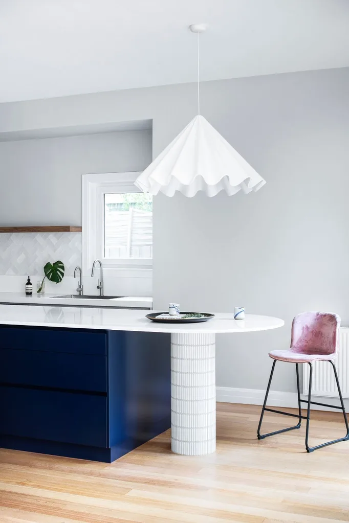 White and navy curved kitchen island bench and dancing pendant light