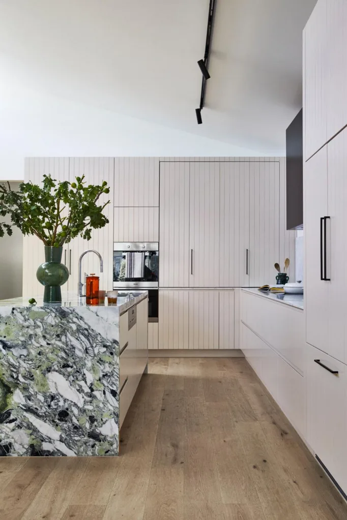 Pink kitchen with green marble waterfall kitchen island bench