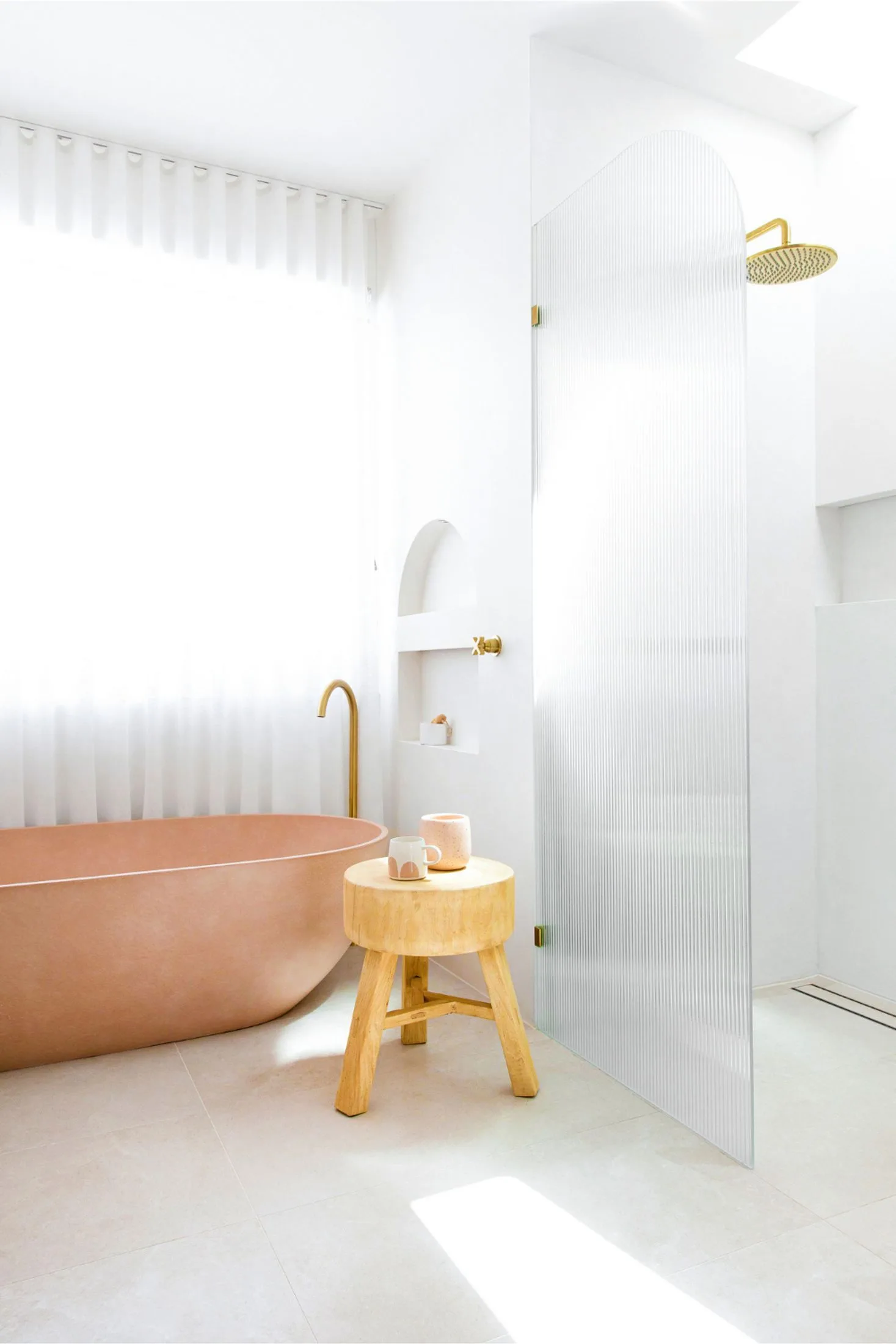 Modern coastal bathroom with a pink freestanding bath and wall niches