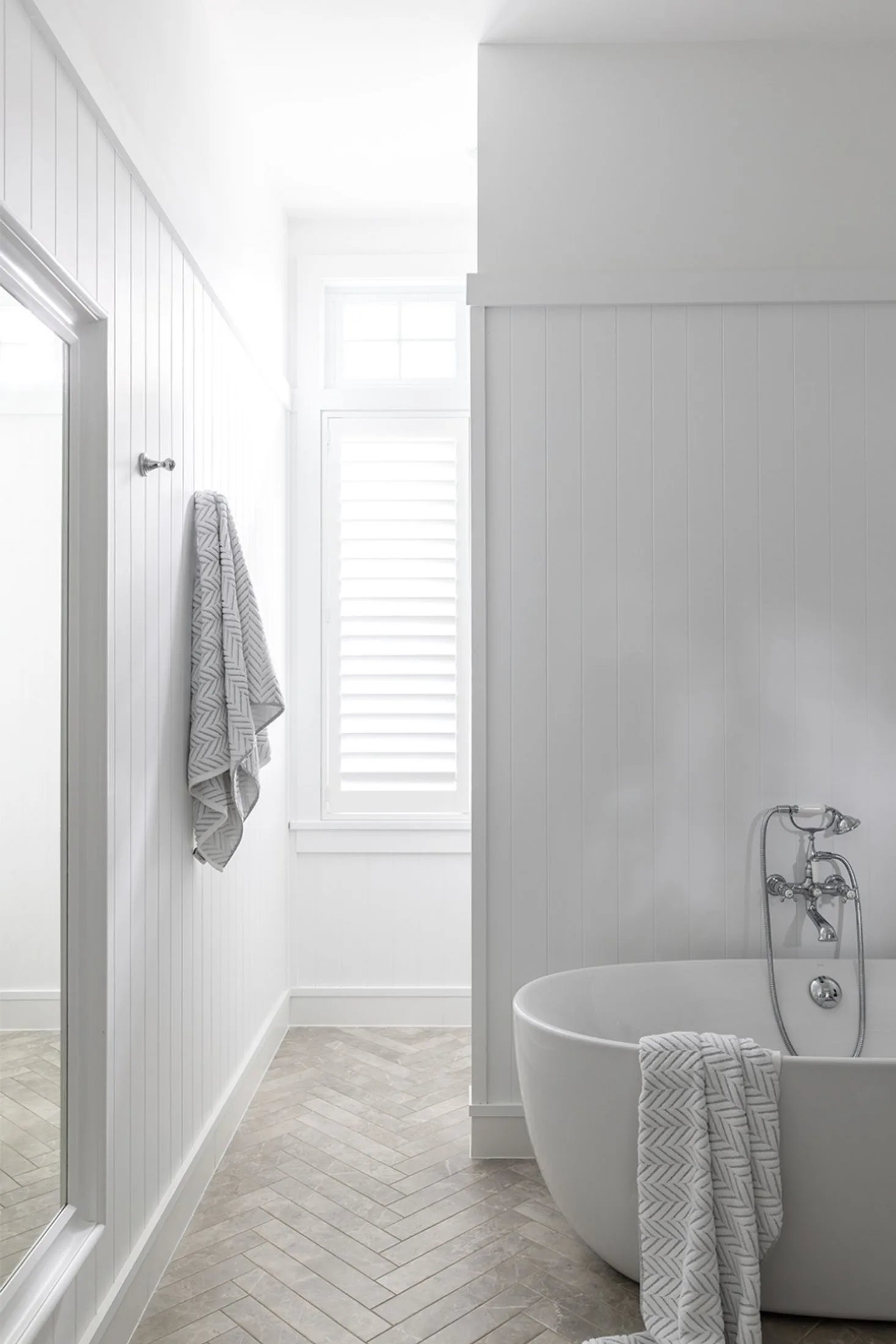 Large white bathroom with freestanding bath, nib wall and VJ-panelling