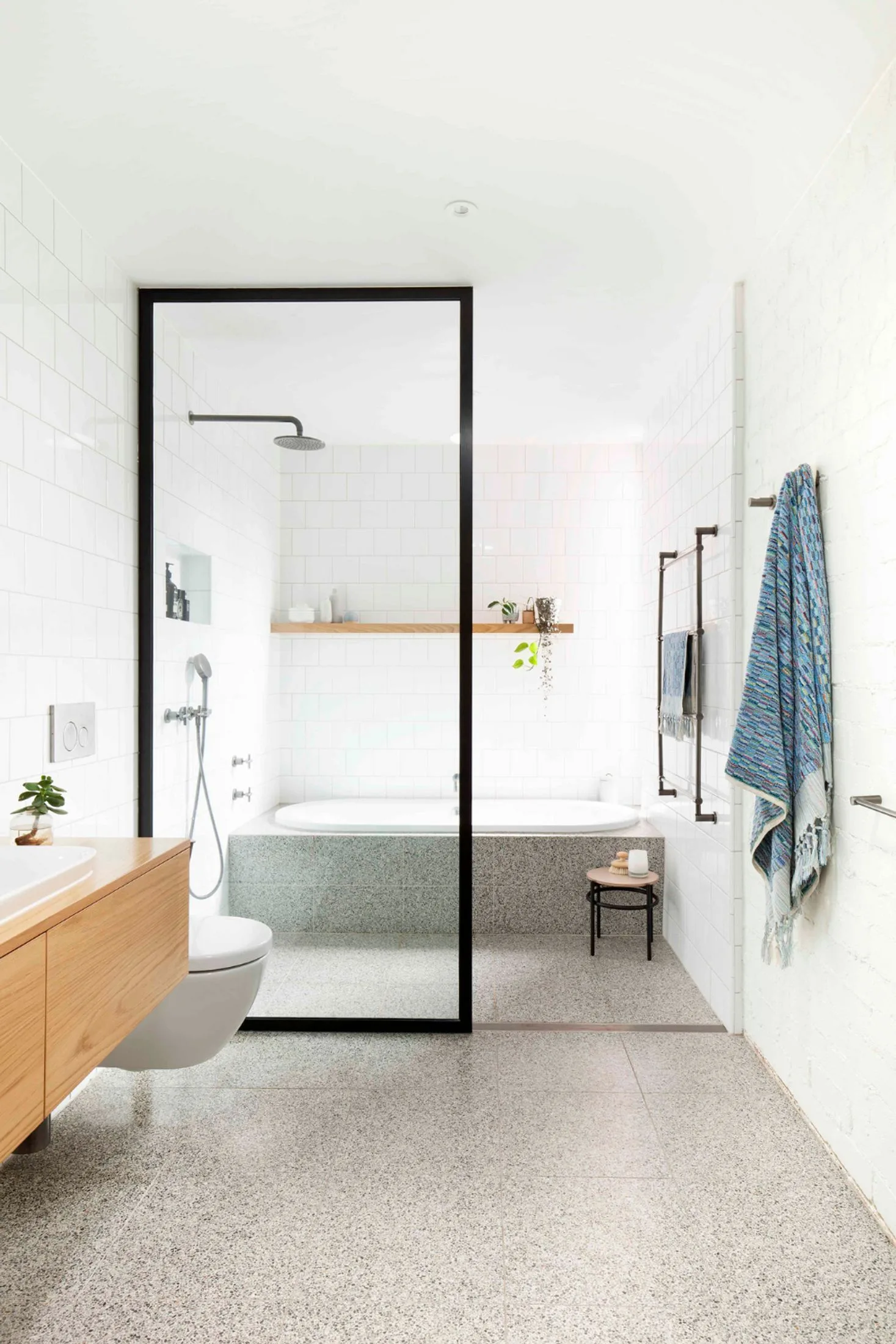 Modern and cosy bathroom with terrazzo tiles and a black-framed shower screen