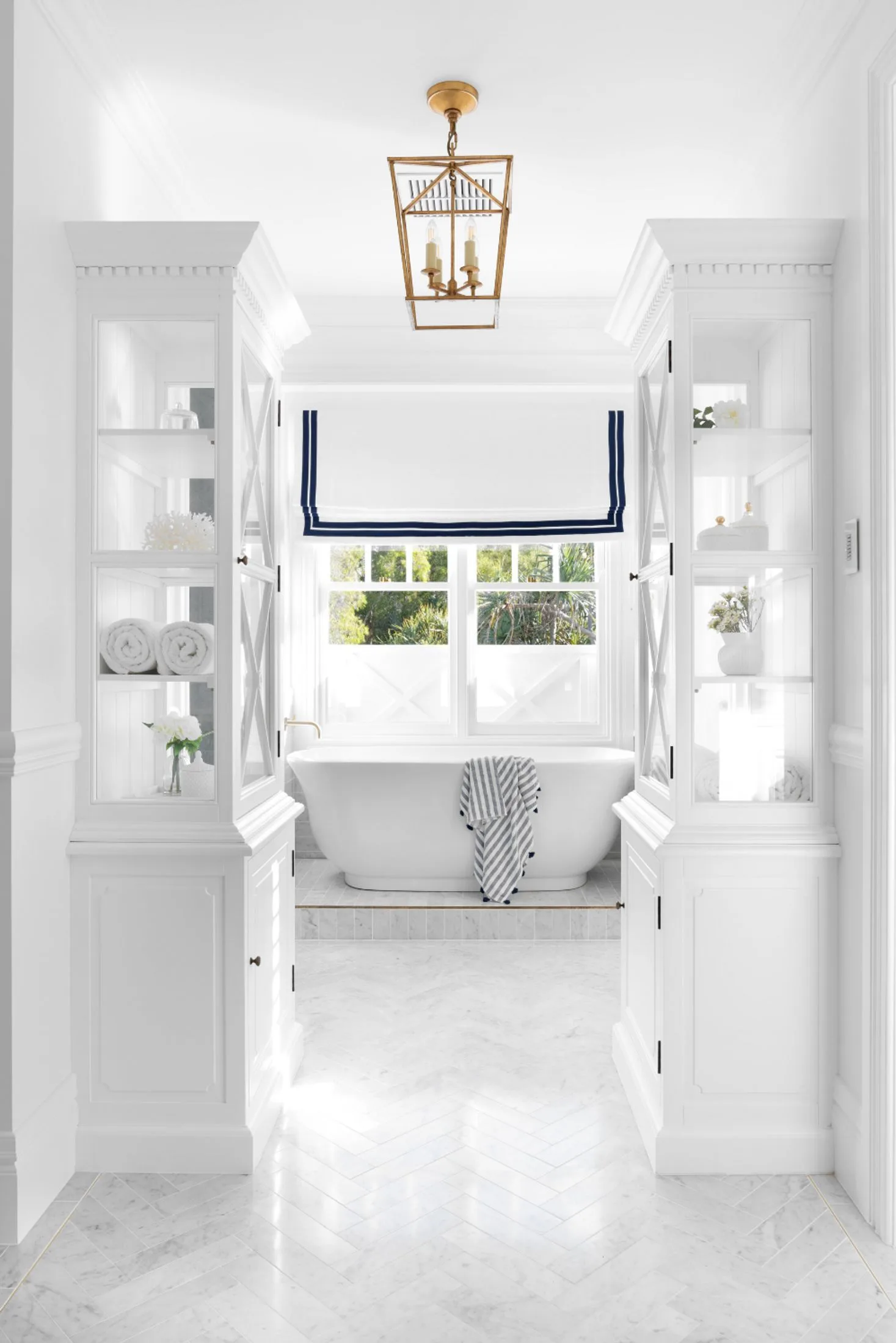 Elegant white Hamptons bathroom with freestanding bath and display cabinets