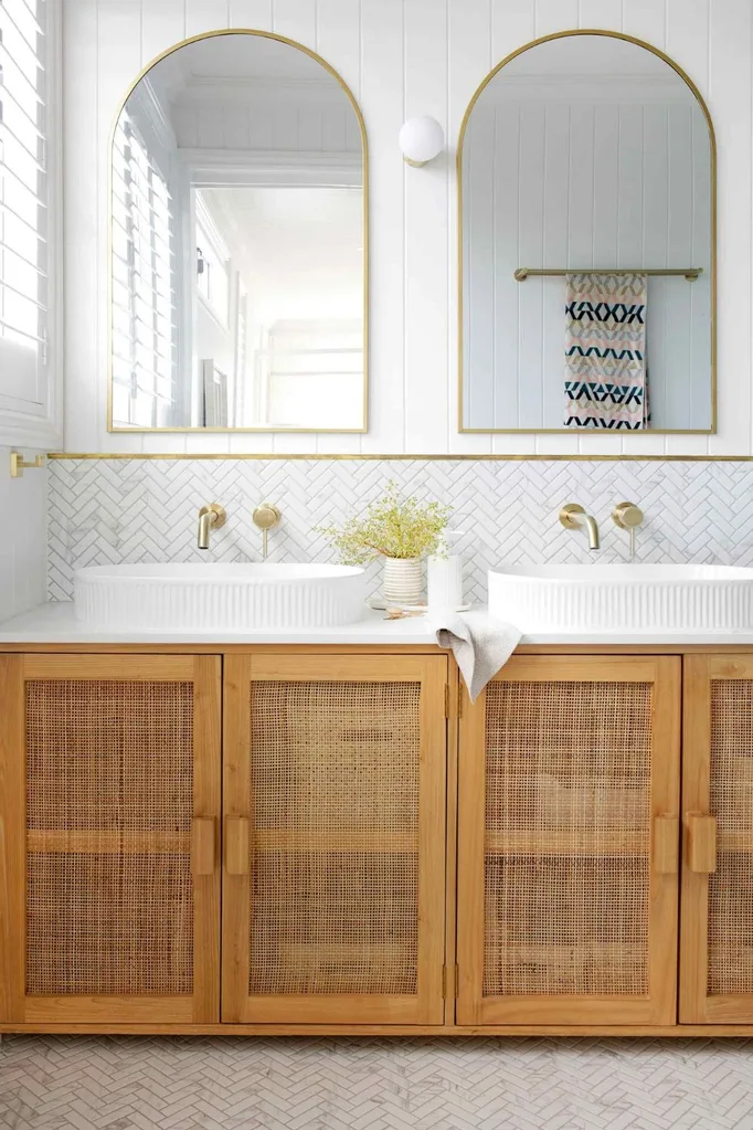 Luxury bathroom with dual sinks, arched mirrors and a rattan vanity