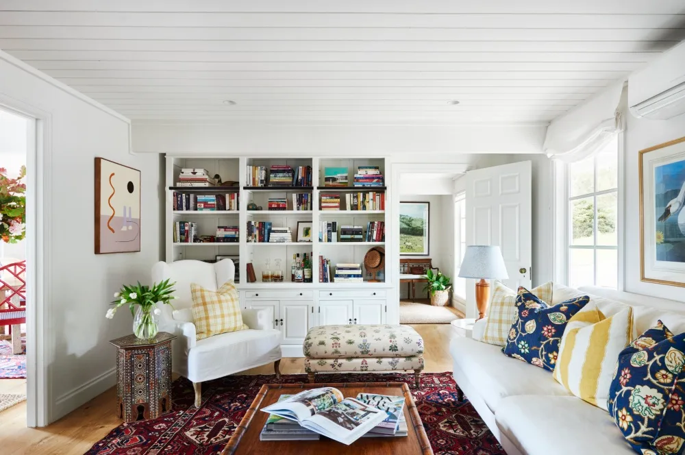 1970s renovation living room with bookshelf and white sofa and white armchair