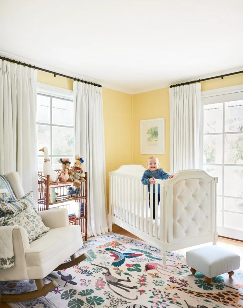 Pale yellow nursery with white tufted cot and bright animal rug