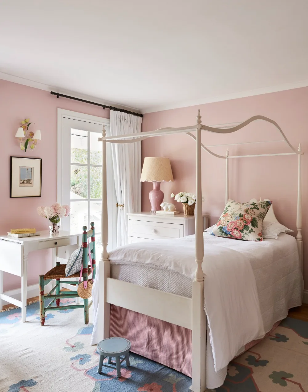 Pink kids bedroom with single 4 poster bed and blue floral round rug