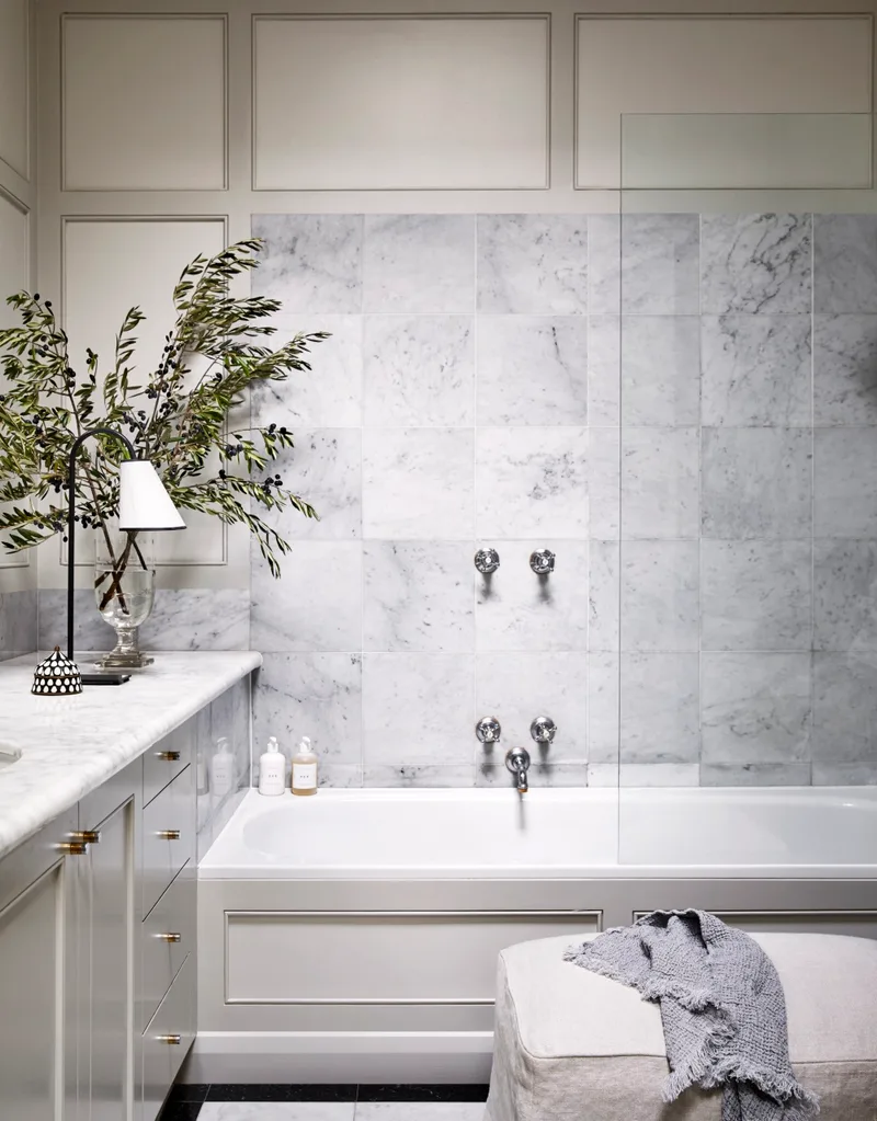 white bathroom with large square marble tile and set in bathtub