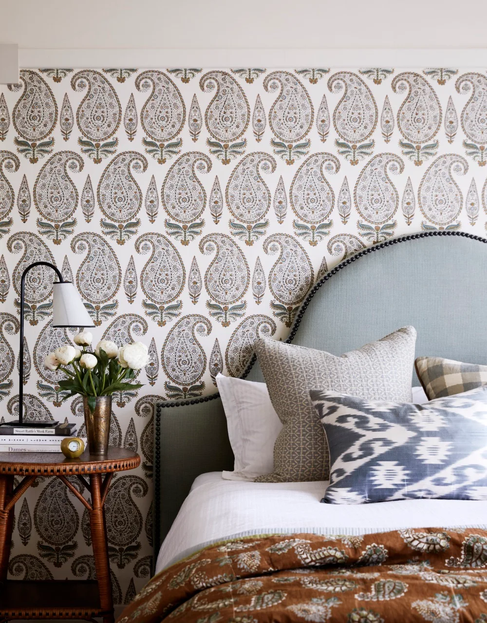Main bedroom with upholstered pale blue bedhead and paisley wallpaper