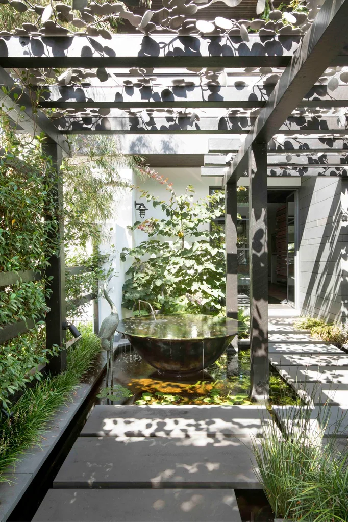 Back garden with vertical garden and large urn water feature under pergola