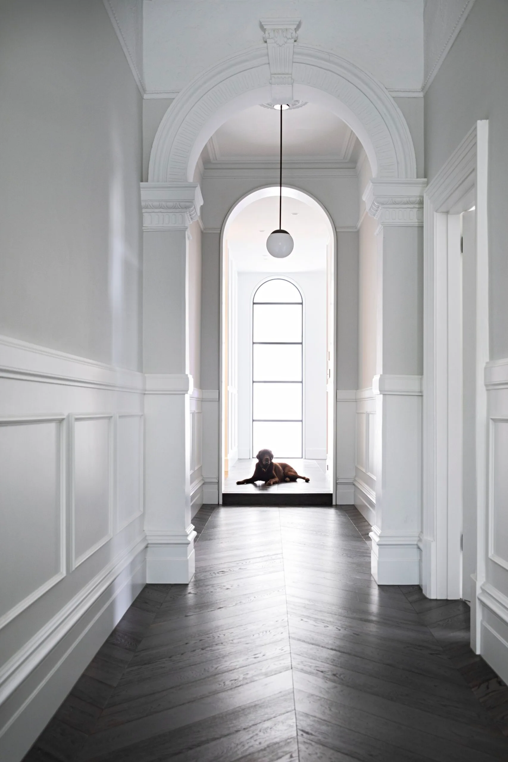 Long hallway with arched details and a dog sitting right at the end.