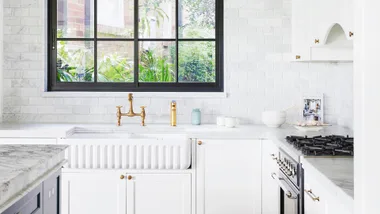 Clean white and marble kitchen with brass hardware.