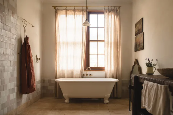 Modern country bathroom with clawfoot bathtub and vintage style curtains.