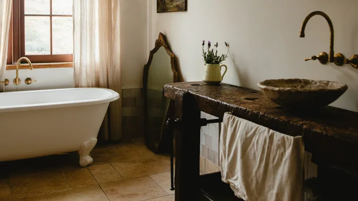 Modern country bathroom with wooden basin and clawfoot bathtub.