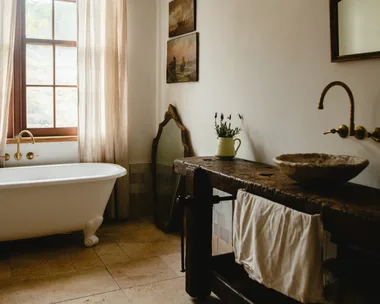 Modern country bathroom with wooden basin and clawfoot bathtub.