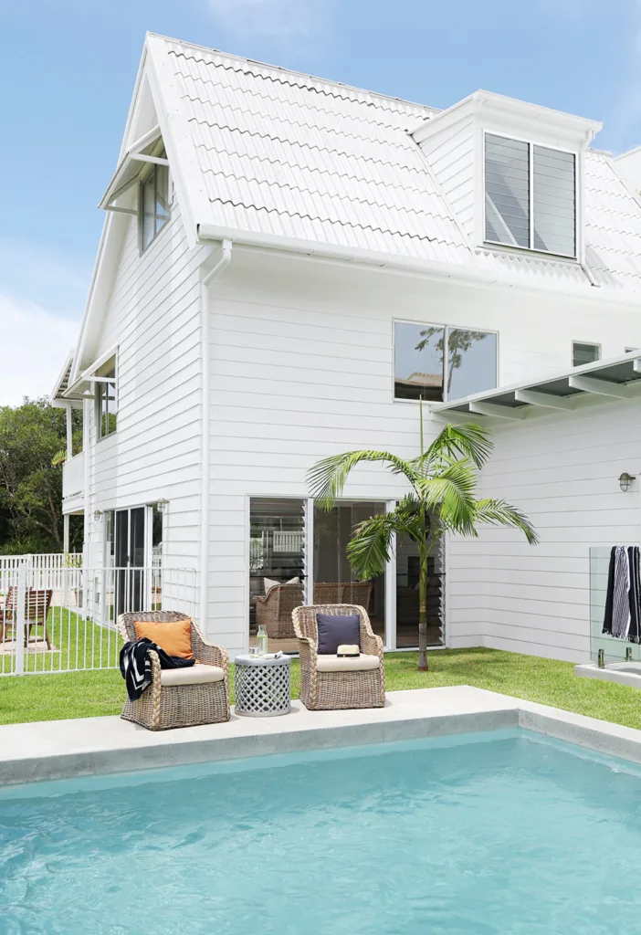 Hamptons white beach house with peaked roof and pool.