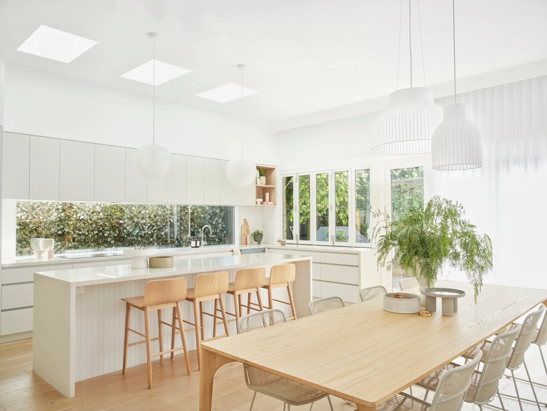 Contemporary renovated Scandi style kitchen with window splashback and skylights.