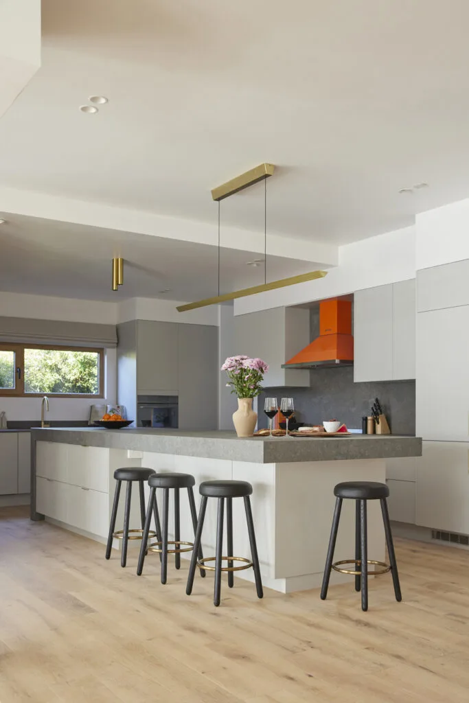 White, grey and orange kitchen with statement Smeg appliances and sink and stovetop located in the kitchen's perimeter.