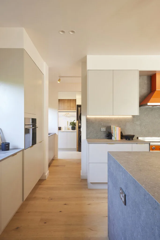 Grey, white and orange kitchen that flows onto the butlers pantry and laundry.