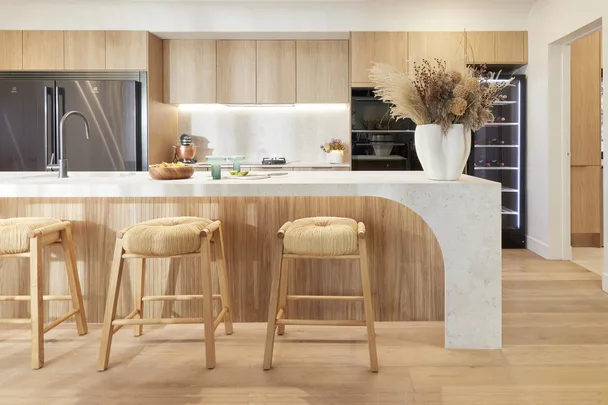 Warm timber kitchen with arched timber island bench and woven bar stools.