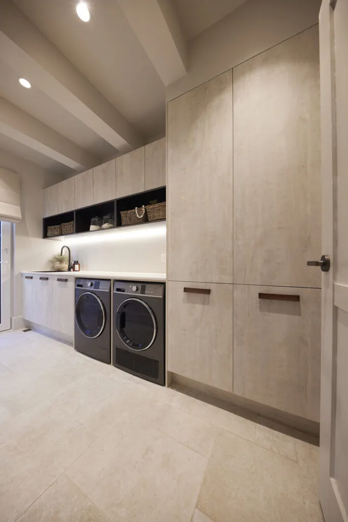 Japandi style laundry with stone floor and dark appliances.