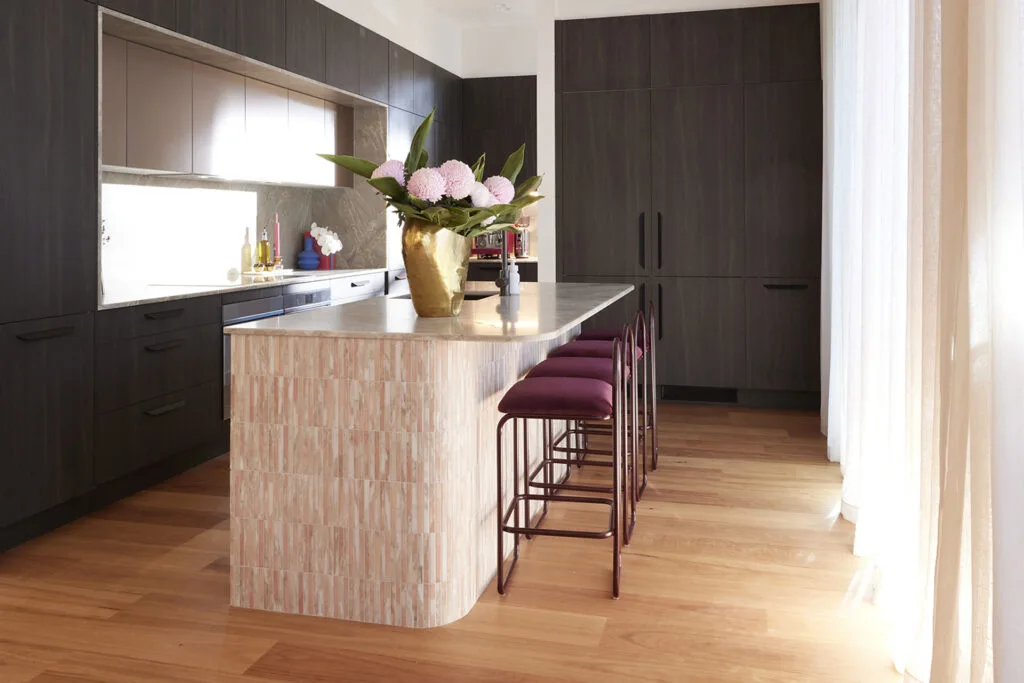 Glamorous dark kitchen with metallic upper cabinets and tiled curved island bench.