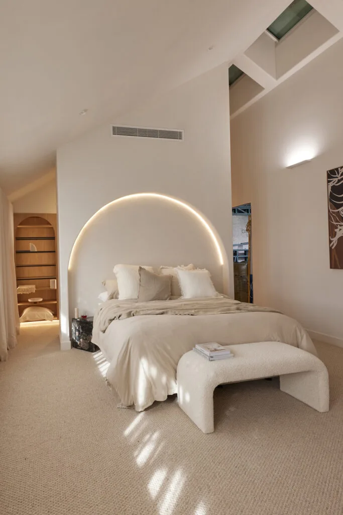 Contemporary neutral master bedroom with boucle bench seat and arch wall bedhead.