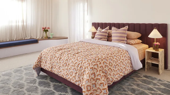 Neutral master bedroom with red velvet bedhead and patterned quilt cover.