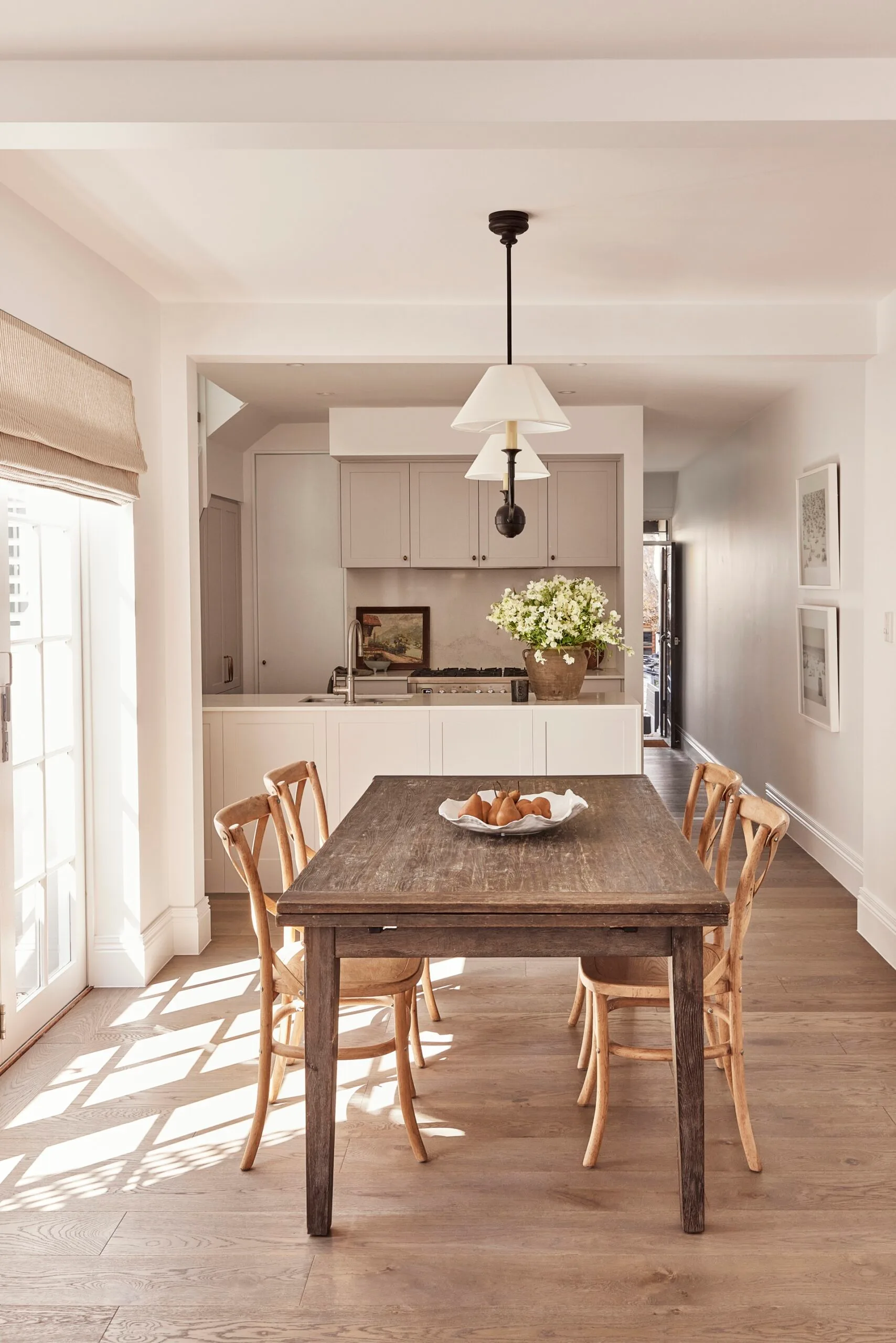 A neutral coloured dining area leading to the kitchen with hybrid floors