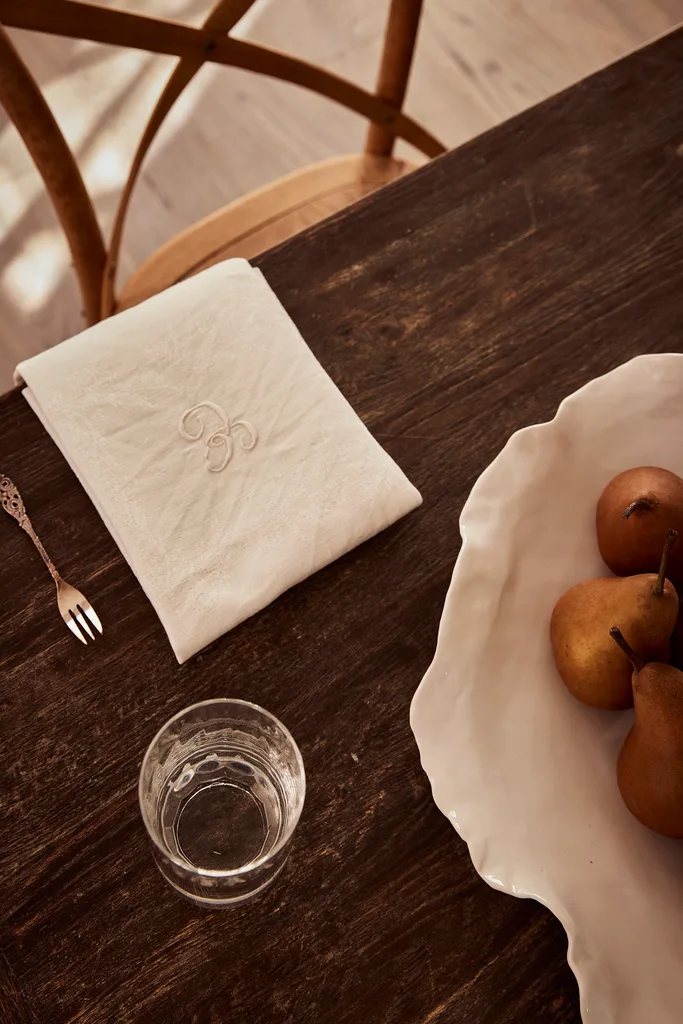 An oak dining table and monogramed napkin.