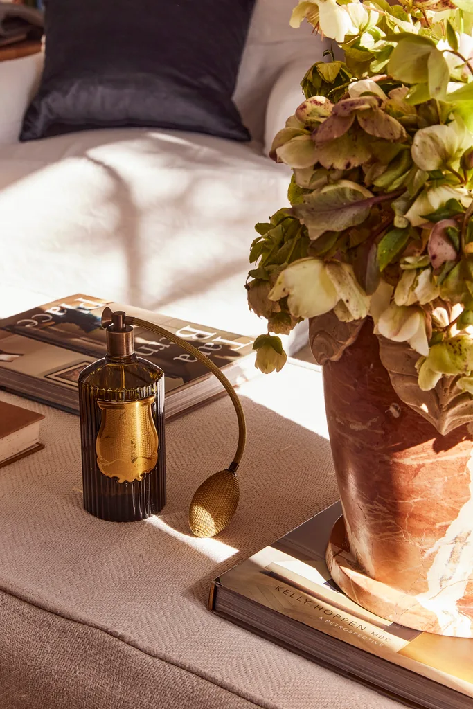 A vintage style ottoman with a planter and vintage perfume bottle.