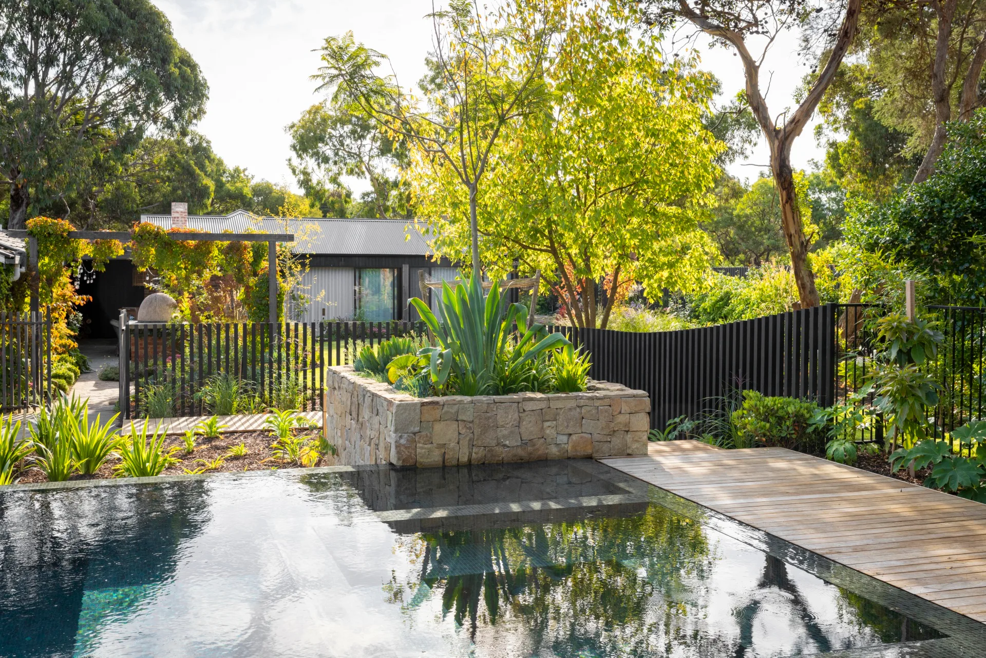 Infinity pool and cottage with gums and stone planter.