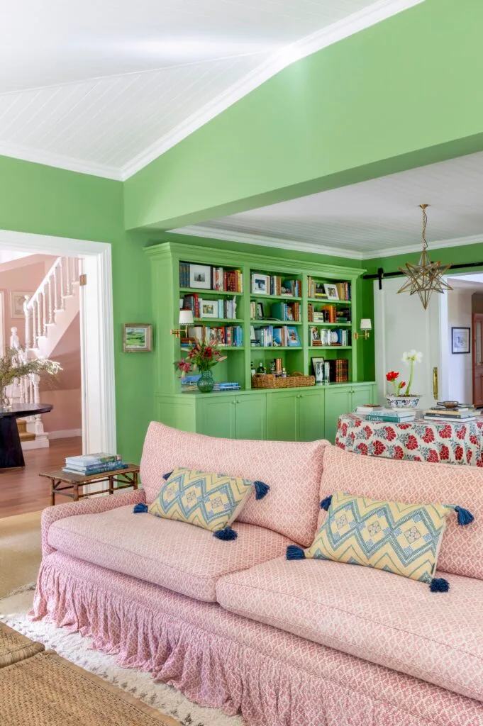 Red patterned living room sofa and green book shelves.