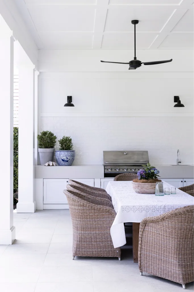 Alfresco outdoor dining with barbeque and white table.