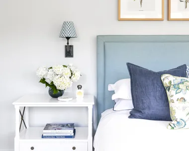 Blue and white contemporary coastal bedroom with side table and soft bedhead.