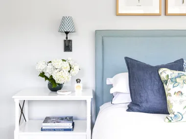 Blue and white contemporary coastal bedroom with side table and soft bedhead.