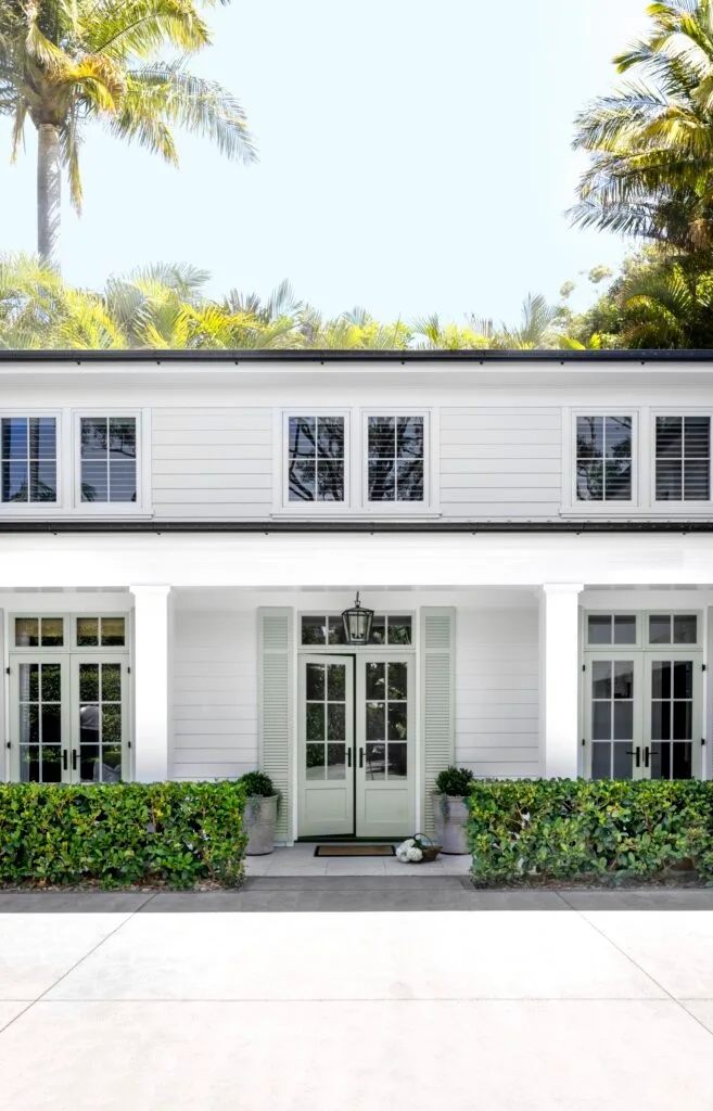 Hamptons home white front facade and garden hedges.