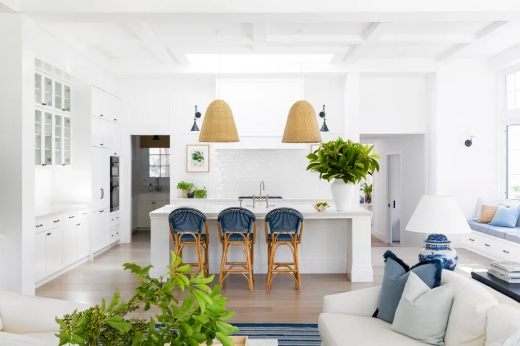 Coastal style white kitchen with blue accents and hanging light pendants.