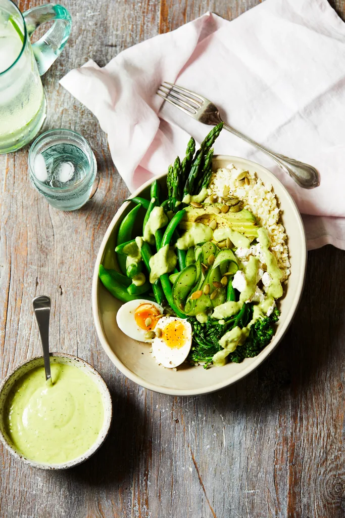 A healthy green breakfast bowl with asparagus and eggs with dressing.
