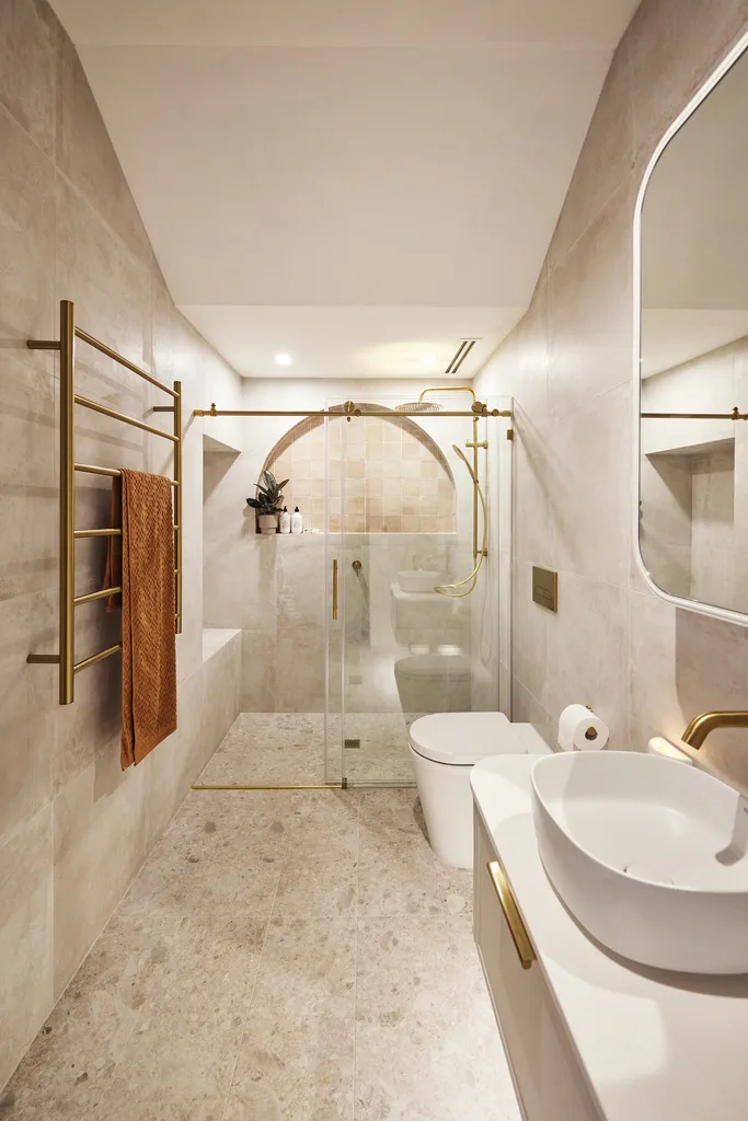 Contemporary neutral bathroom with curved feature niche and brass hardware.
