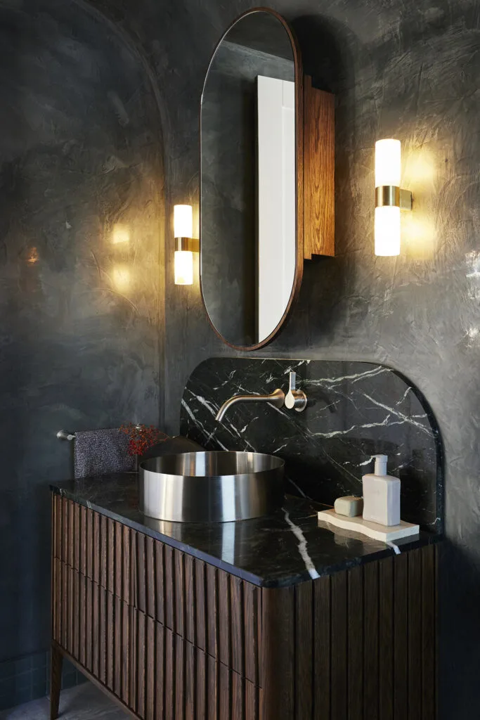 Dark and moody bathroom with black marble, Venetian plaster and dark timber vanity.