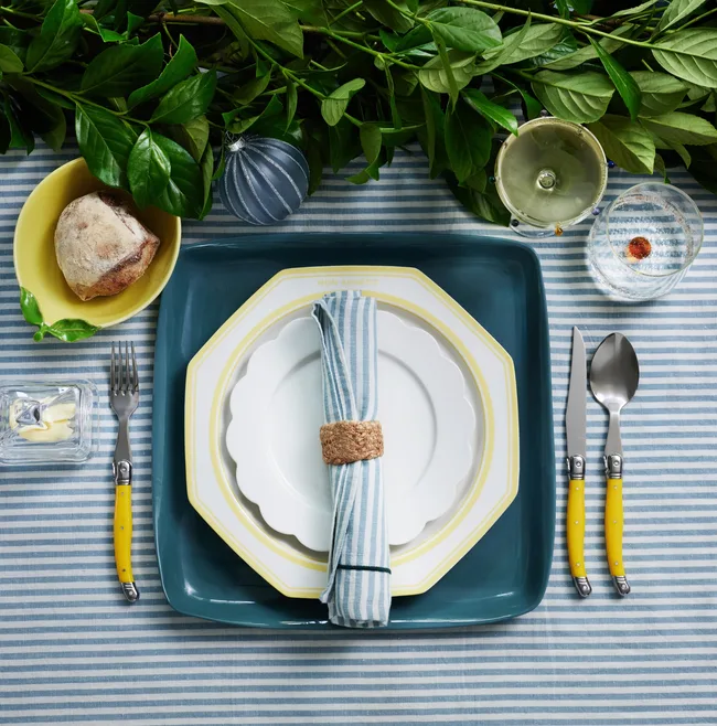 Blue and white striped tablecloth, matching tableware and greenery as the centrepiece