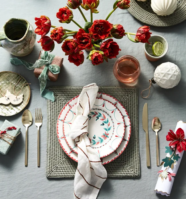 Table setting with red flowers and a muted, soft green table linen
