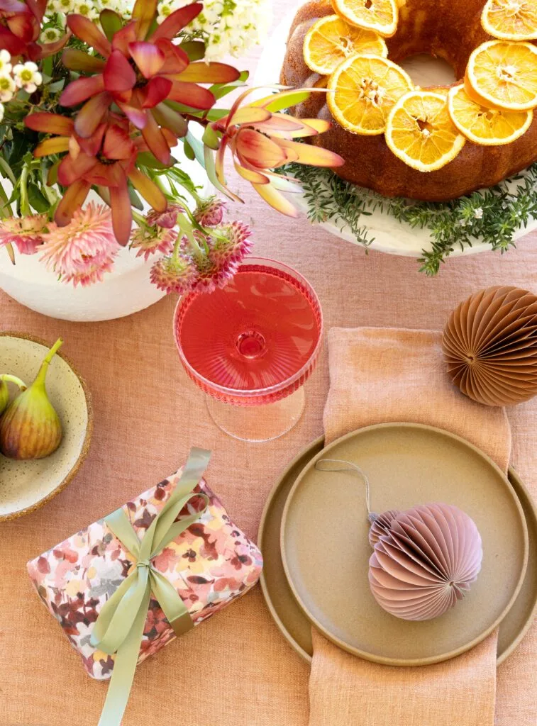 A bright Christmas tablescape with paper decorations and florals.